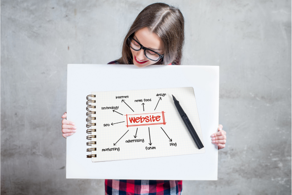 A female small business owner holding a whilte board with a spider diagram on it. She's trying to answer the question of Why Your Website Isn’t Working And How A Blog Can Fix It.